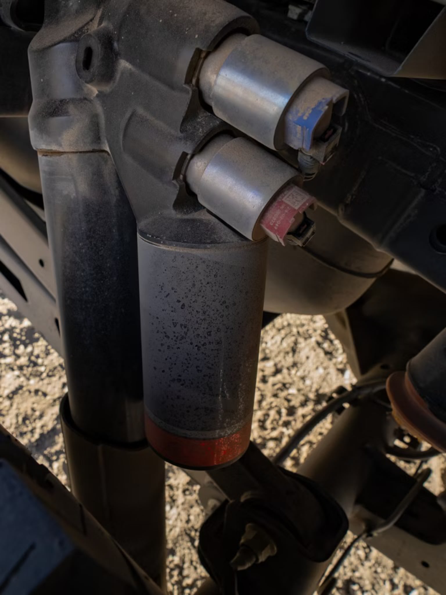 Metal components of a vehicle's suspension system surrounded by dirt and debris.