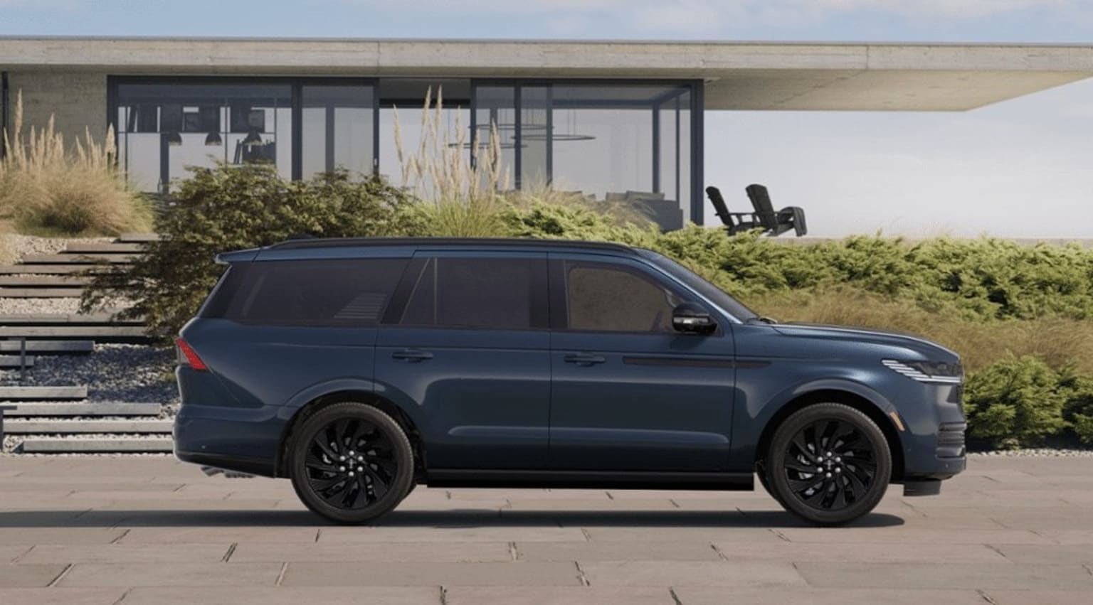 An SUV parked in front of a modern building with glass walls and a landscaped area.
