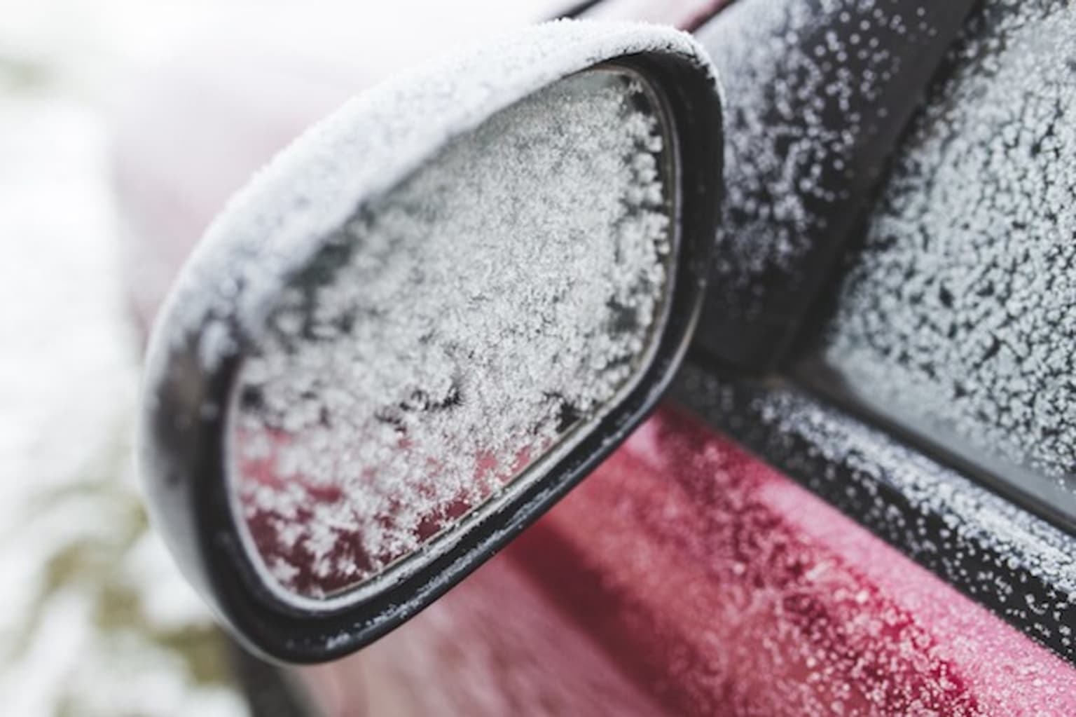 a close up of a car's side view mirror covered in a lot of snow on a snowy day