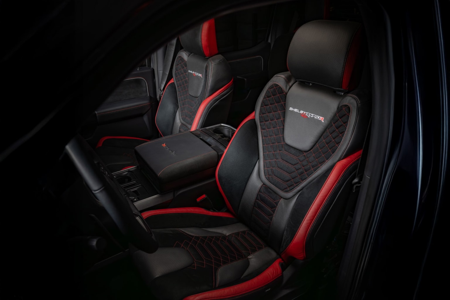 The image shows the interior of a vehicle, with a pair of high-performance sports car seats in the foreground, featuring a sleek black and red design.