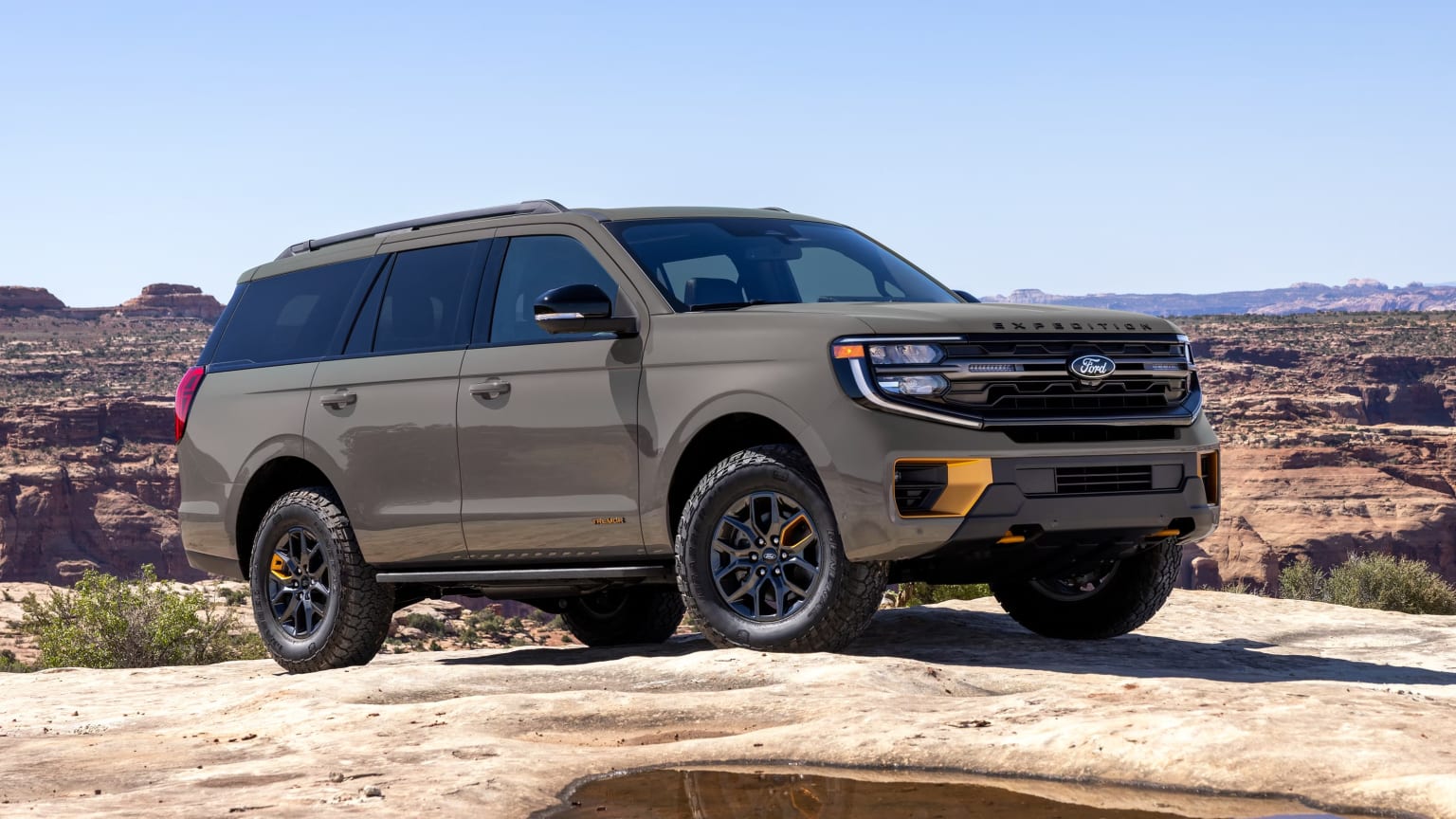 Off-road vehicle on rocky desert terrain with mountain landscape in the background