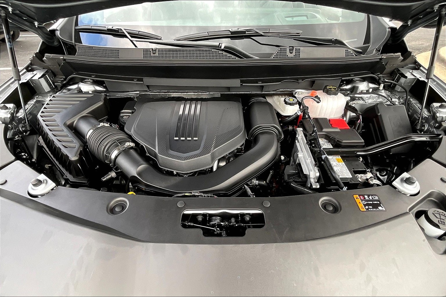 The image shows the engine compartment of a vehicle, with various mechanical components and wiring visible. The background appears to be a clean, well-lit environment, likely a garage or workshop setting.