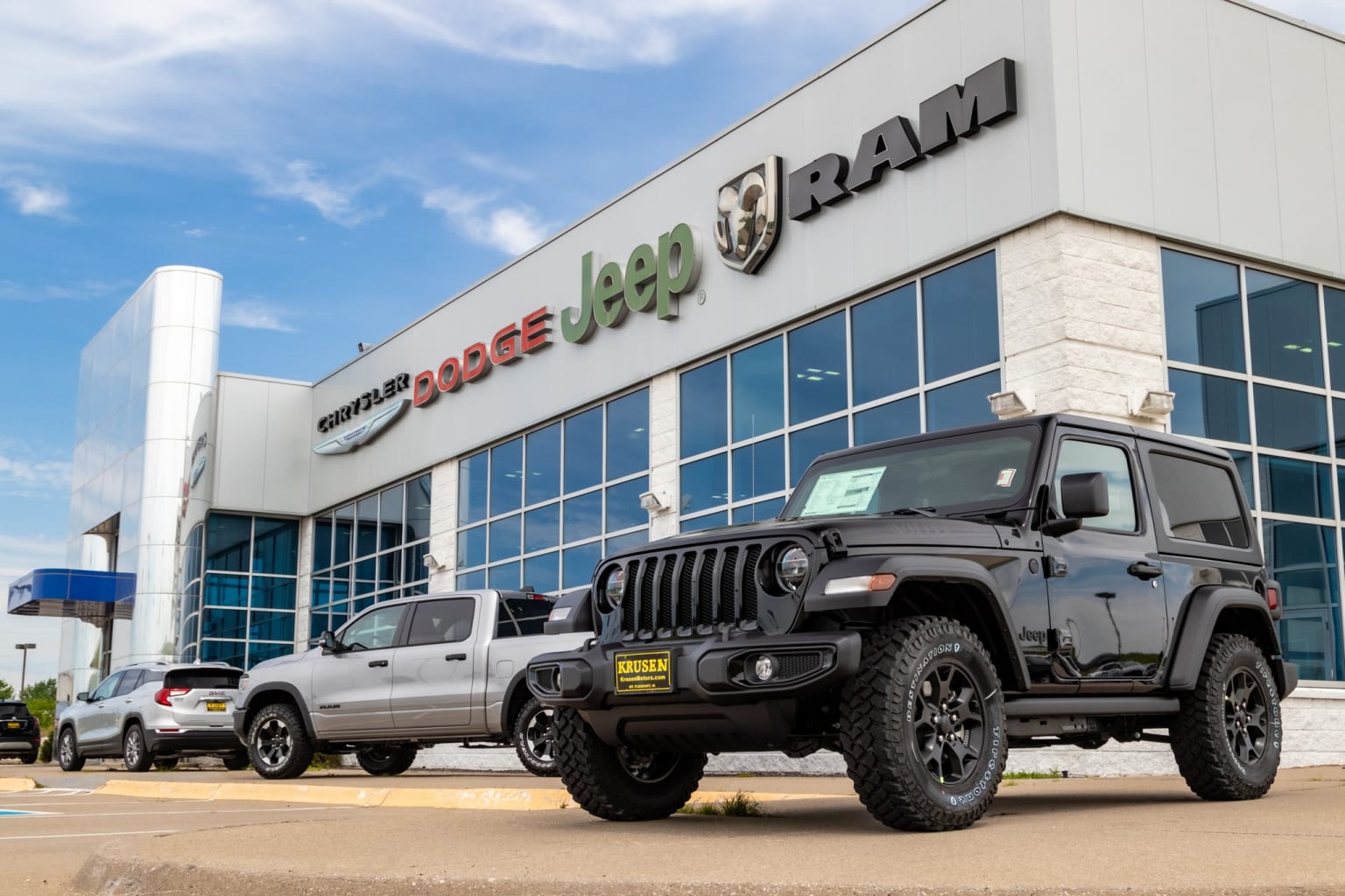 a jeep is parked in front of a jeep dealership with a jeep in the foreground and a jeep in the background