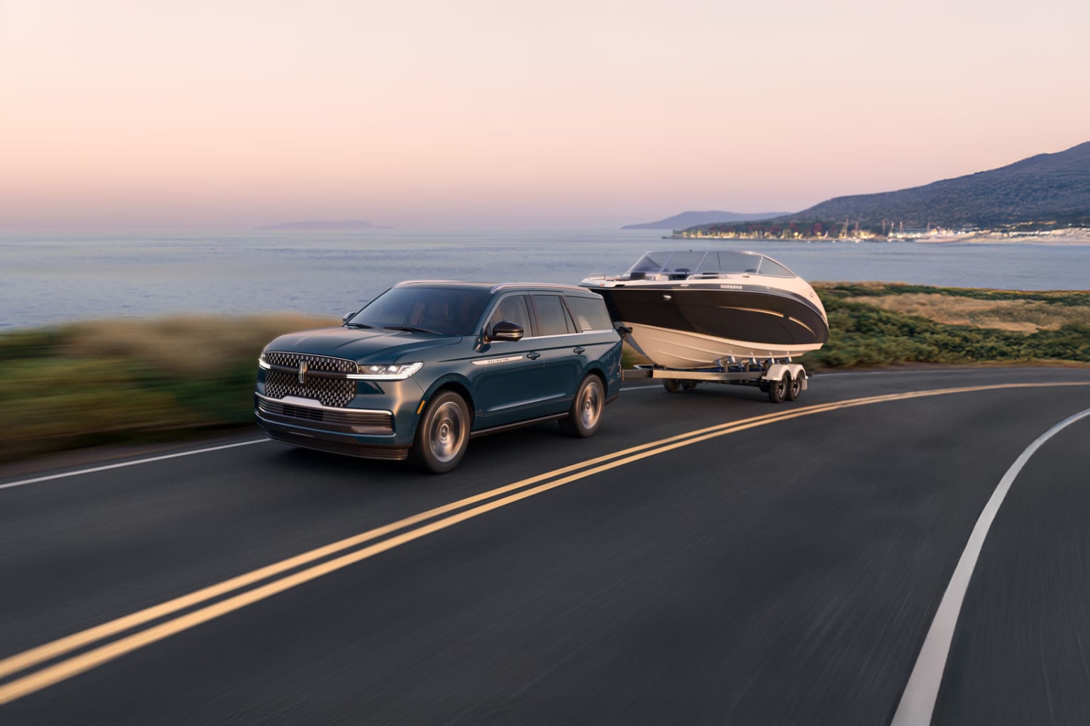 SUV towing a boat trailer on a coastal road with ocean view.