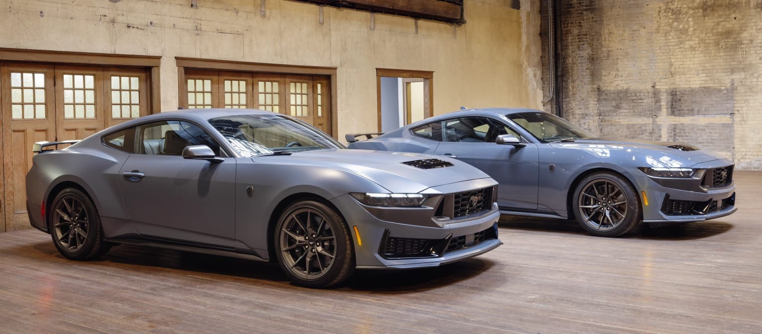 Two sleek and sporty sports cars in an industrial-style building with brick walls and wooden beams.