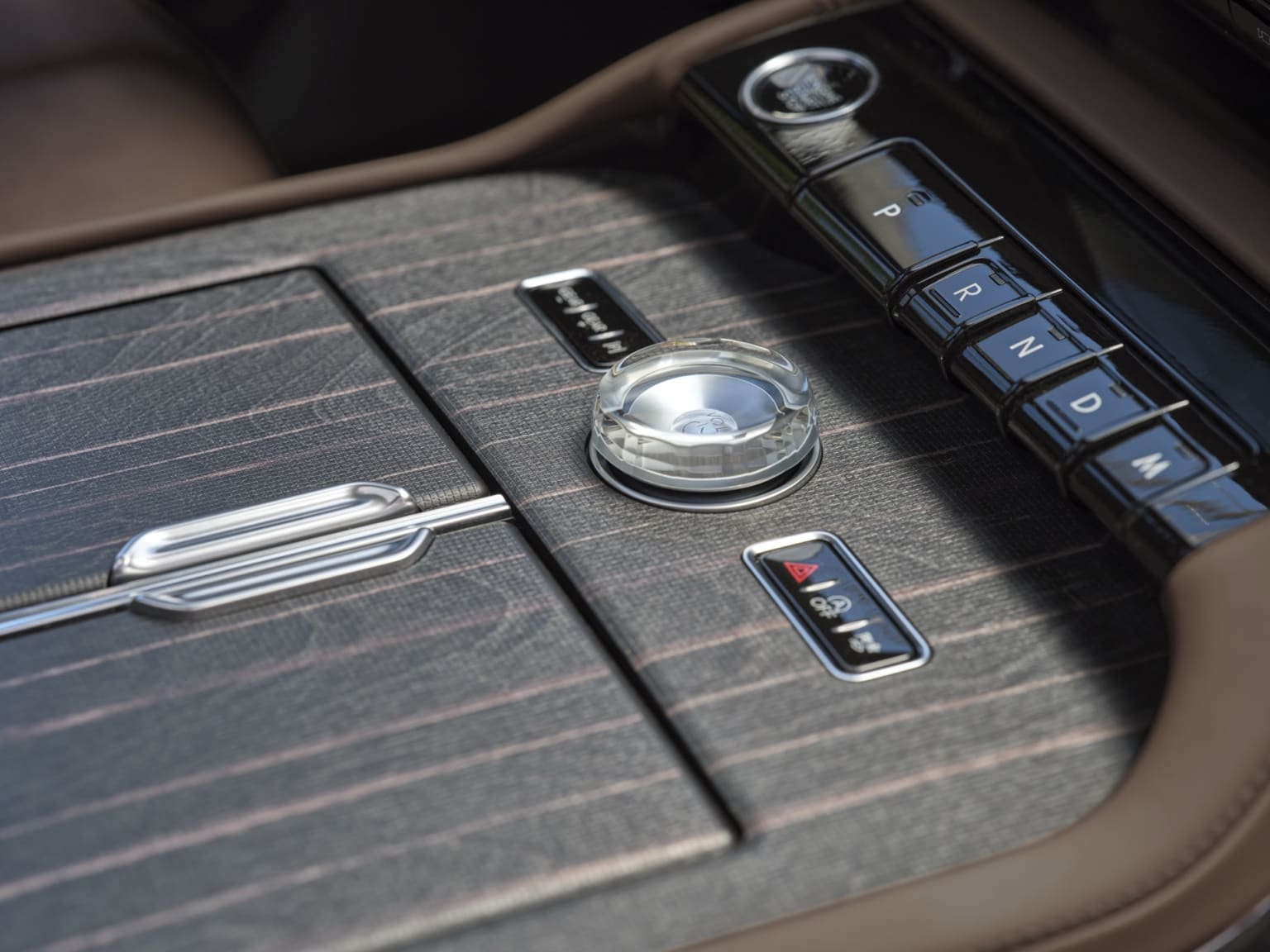 The image displays the interior of a vehicle, showcasing the center console with a gear shift, buttons, and a circular dial.