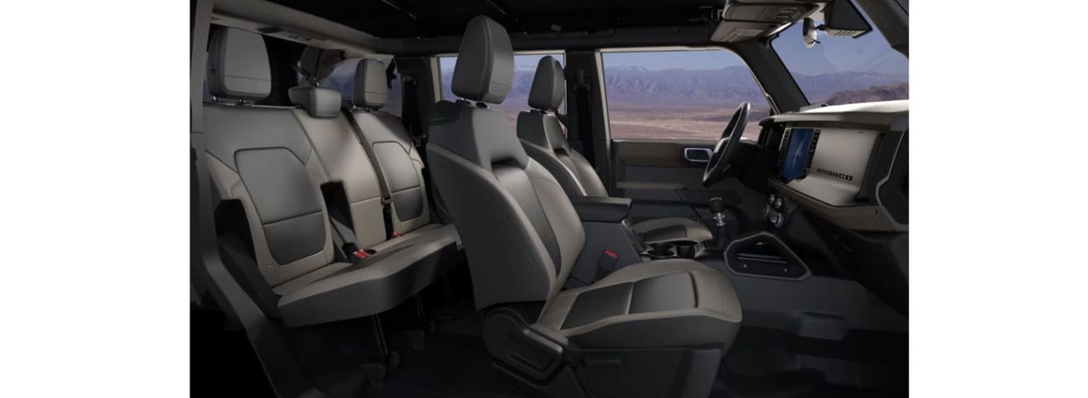 Interior of a vehicle with gray leather seats and a view of mountainous landscape.