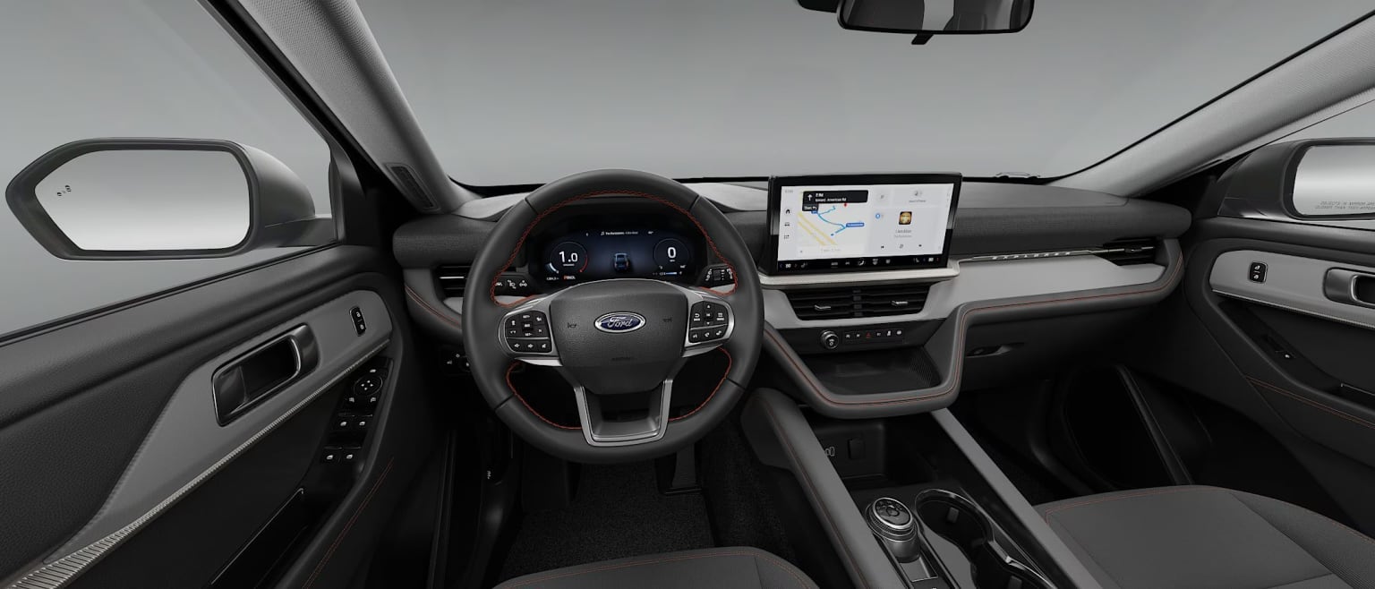 Interior of a modern vehicle with a steering wheel, dashboard, and a large touchscreen display in the center console.