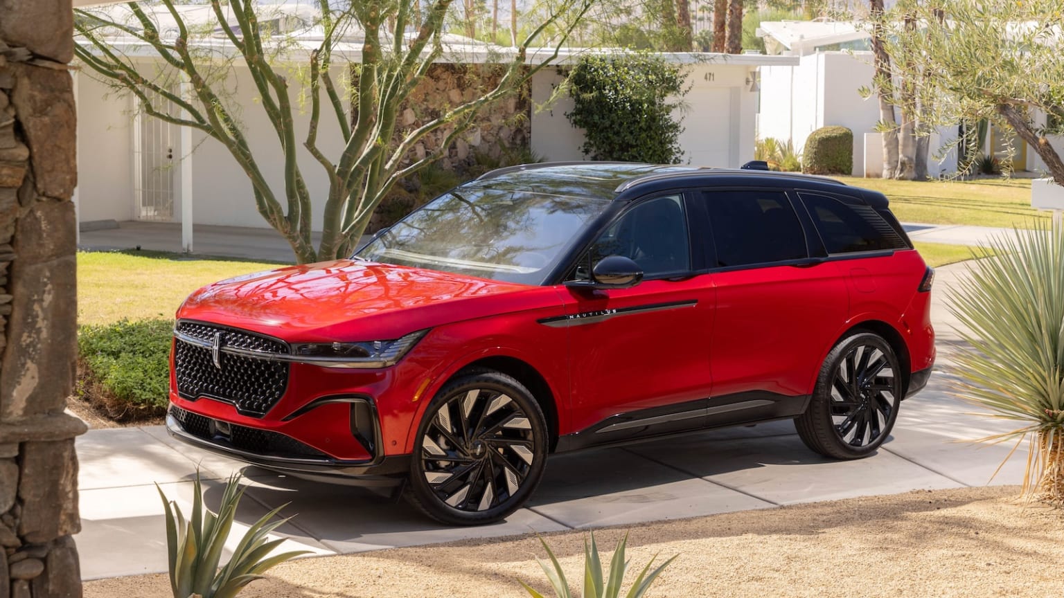 SUV parked in a green environment with trees and a lawn.