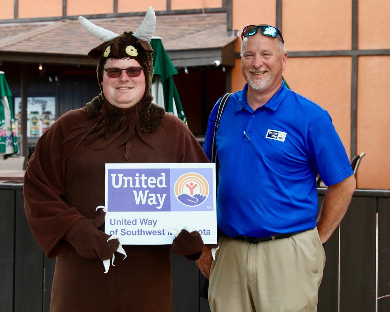 a man in a costume standing next to a man in a costume holding a sign that says united way