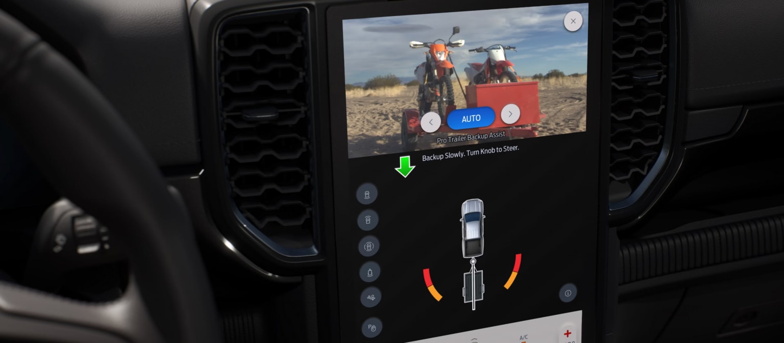 The image depicts a motorcycle with a display screen showing a map or navigation interface. The background features a rural or outdoor setting under a cloudy sky.