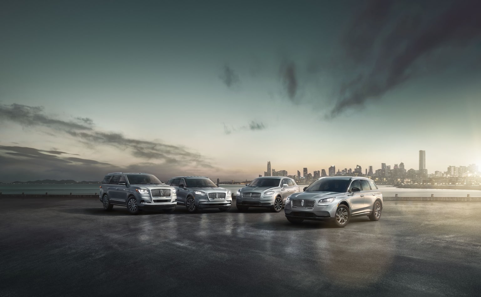 a group of cars parked next to each other in front of a cityscape with a sunset in the background