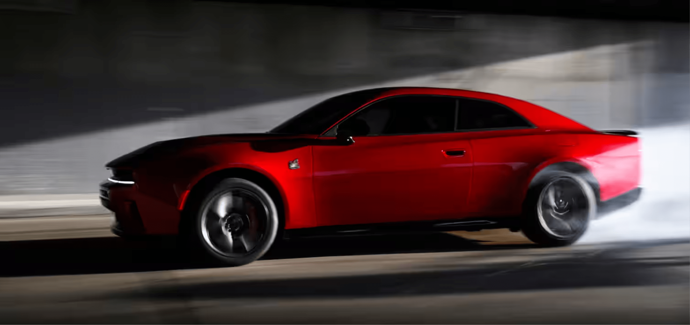 A red sports car drifting on dark pavement, emitting white smoke against a blurred background.
