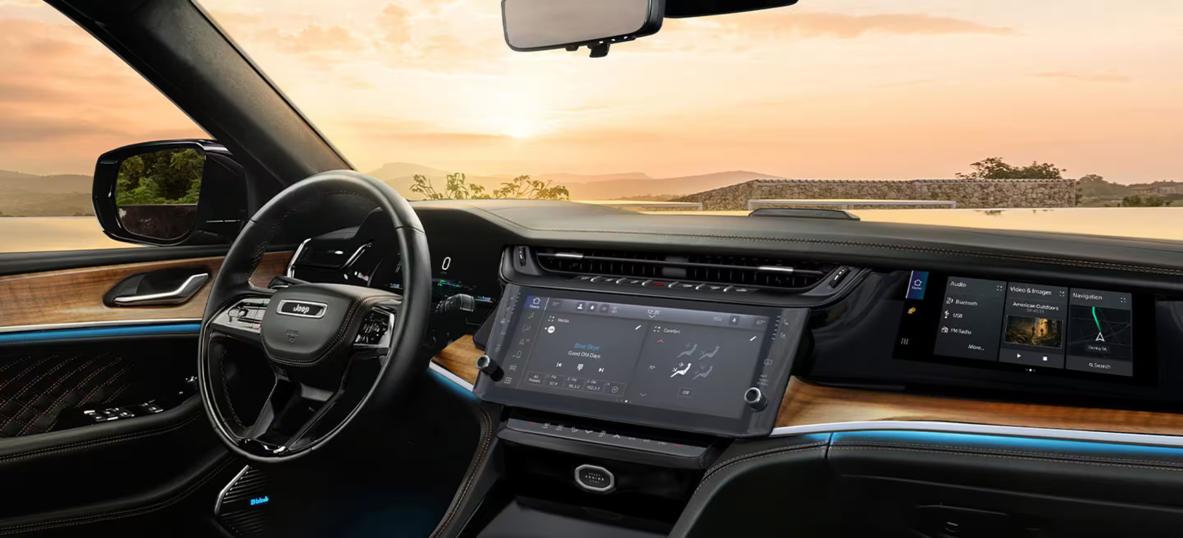 A modern car interior with digital displays and a leather steering wheel with a scenic sunset landscape visible through the windshield.