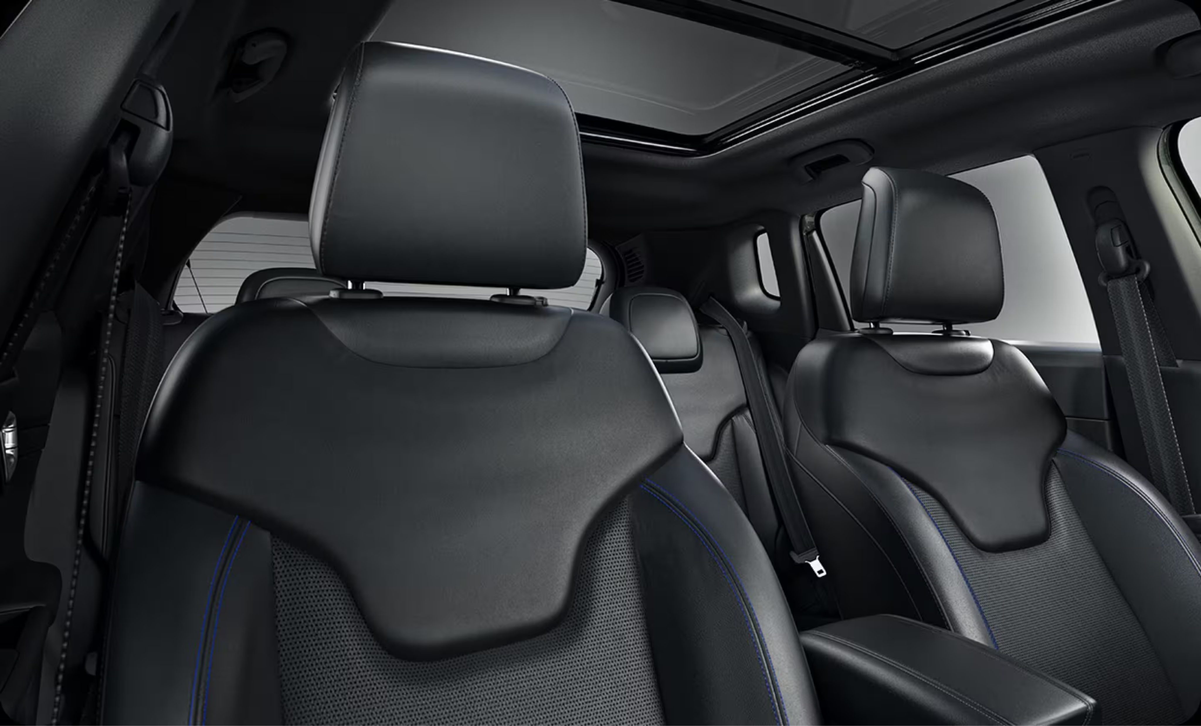 Black leather car seats with blue stitching and a panoramic sunroof.