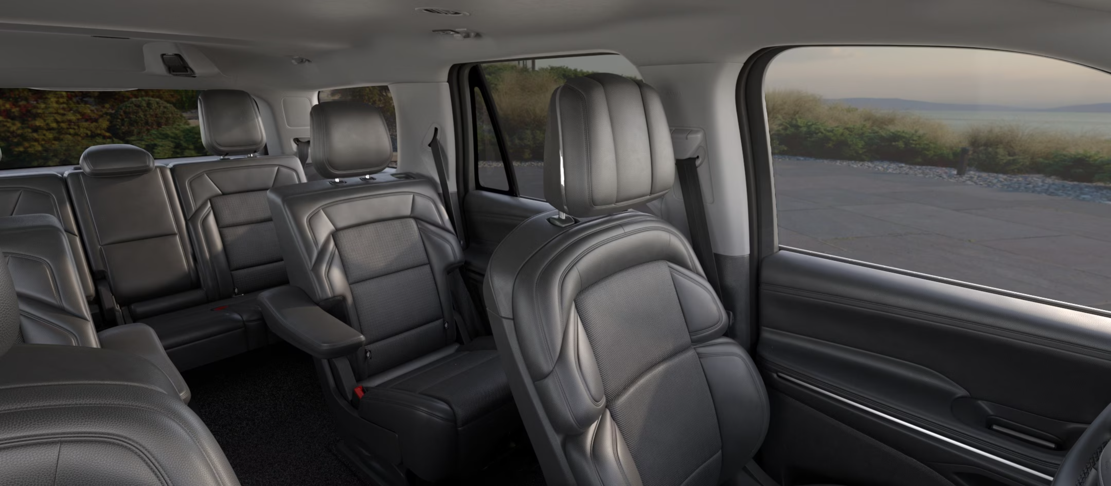 Black leather seats in a luxury car interior with a view of the ocean through the windows.
