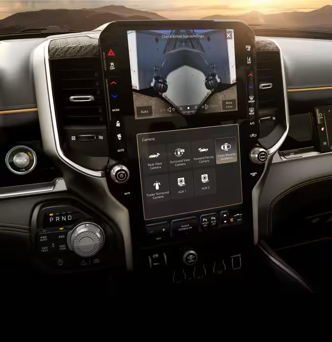 Modern car dashboard with digital display and camera views against sunset mountains.