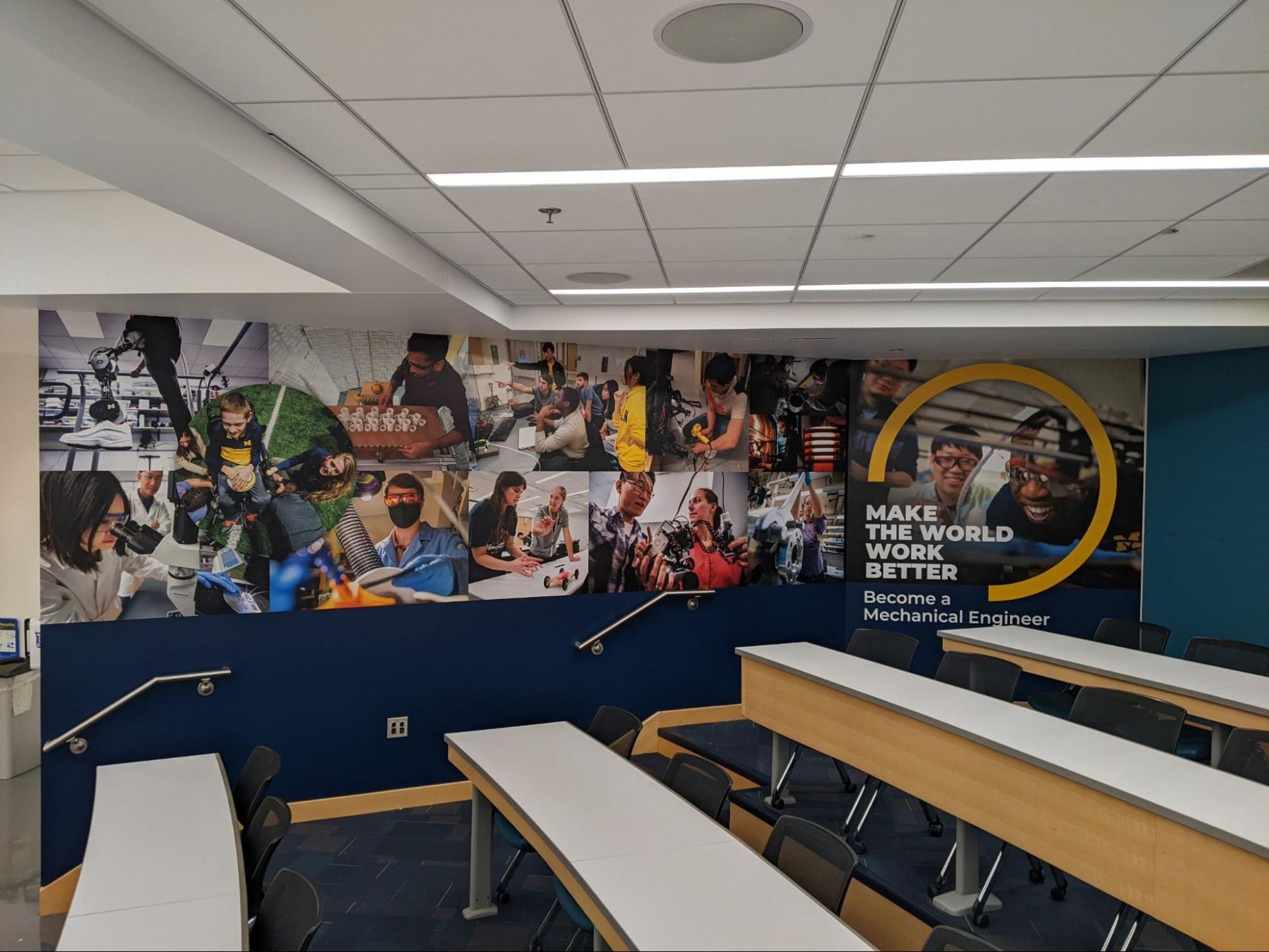 A classroom wall display that showcases a collage of images from the "Share Our Stories" profiles, capturing the diversity and vibrancy of the U-M ME community while emphasizing how we "Make the World Work Better."