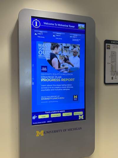 A digital sign in a campus building with an ad on the screen