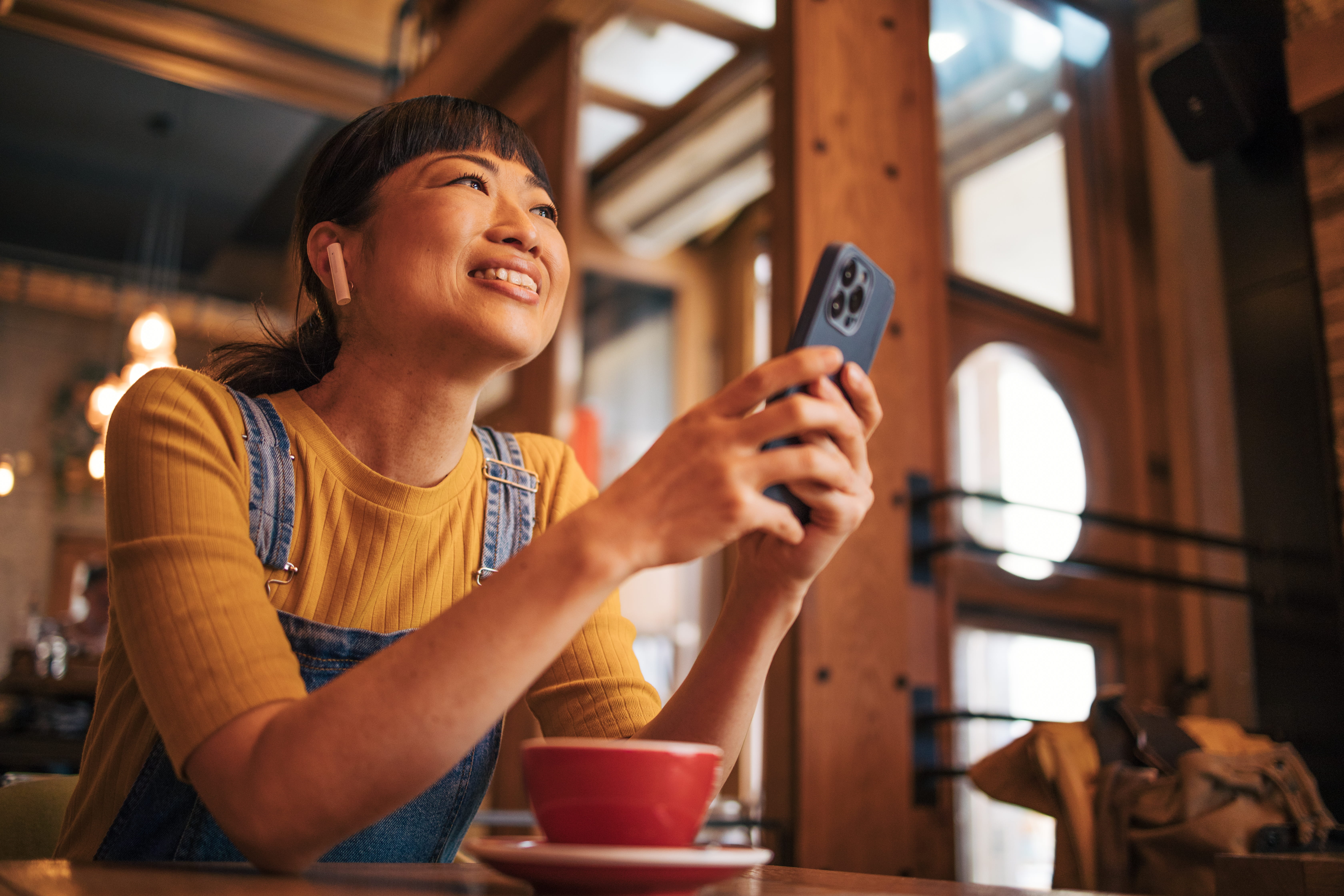 Woman in a cafe with coffee, browsing Rogers plans on her phone