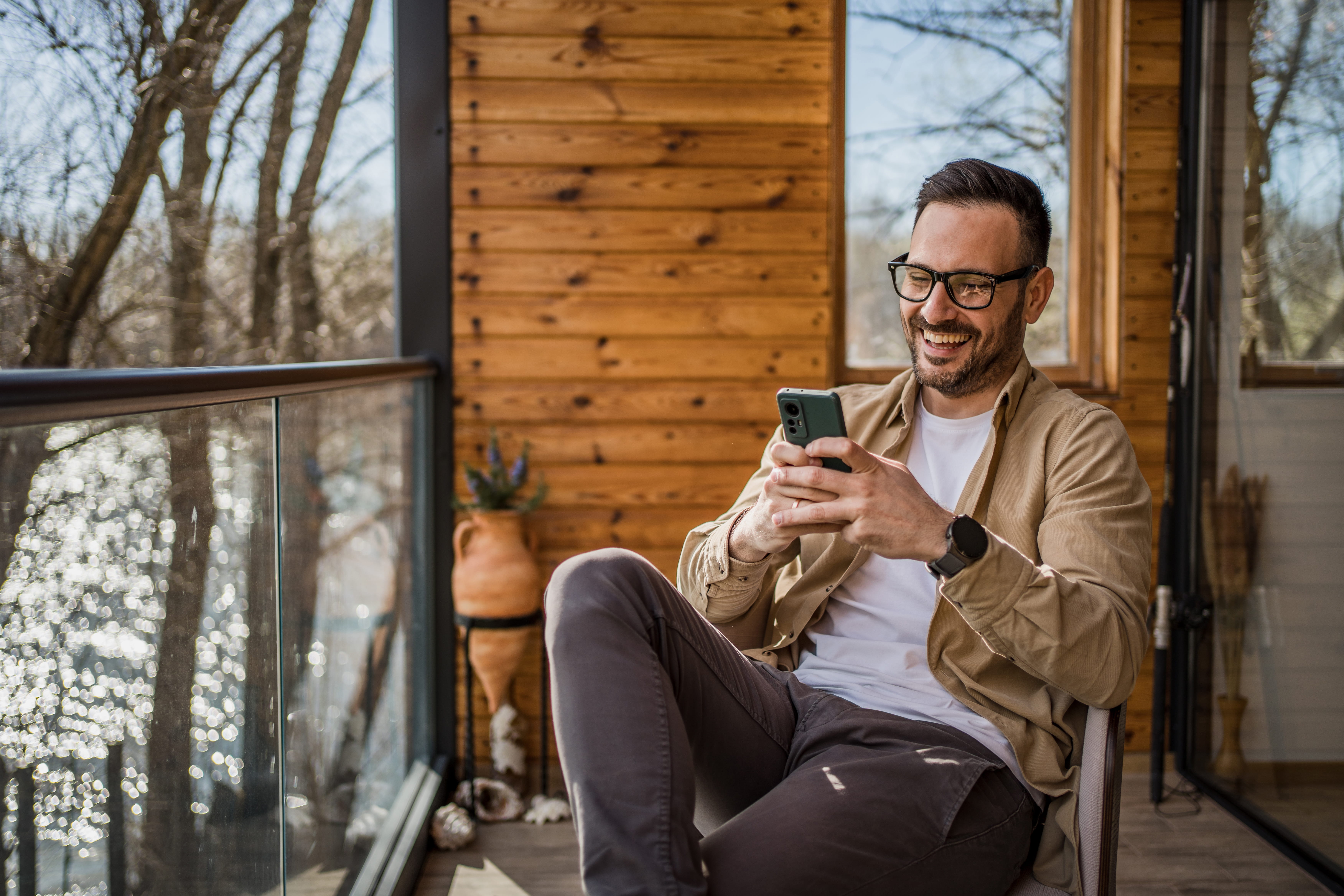 Man relaxing on his home patio while using his phone