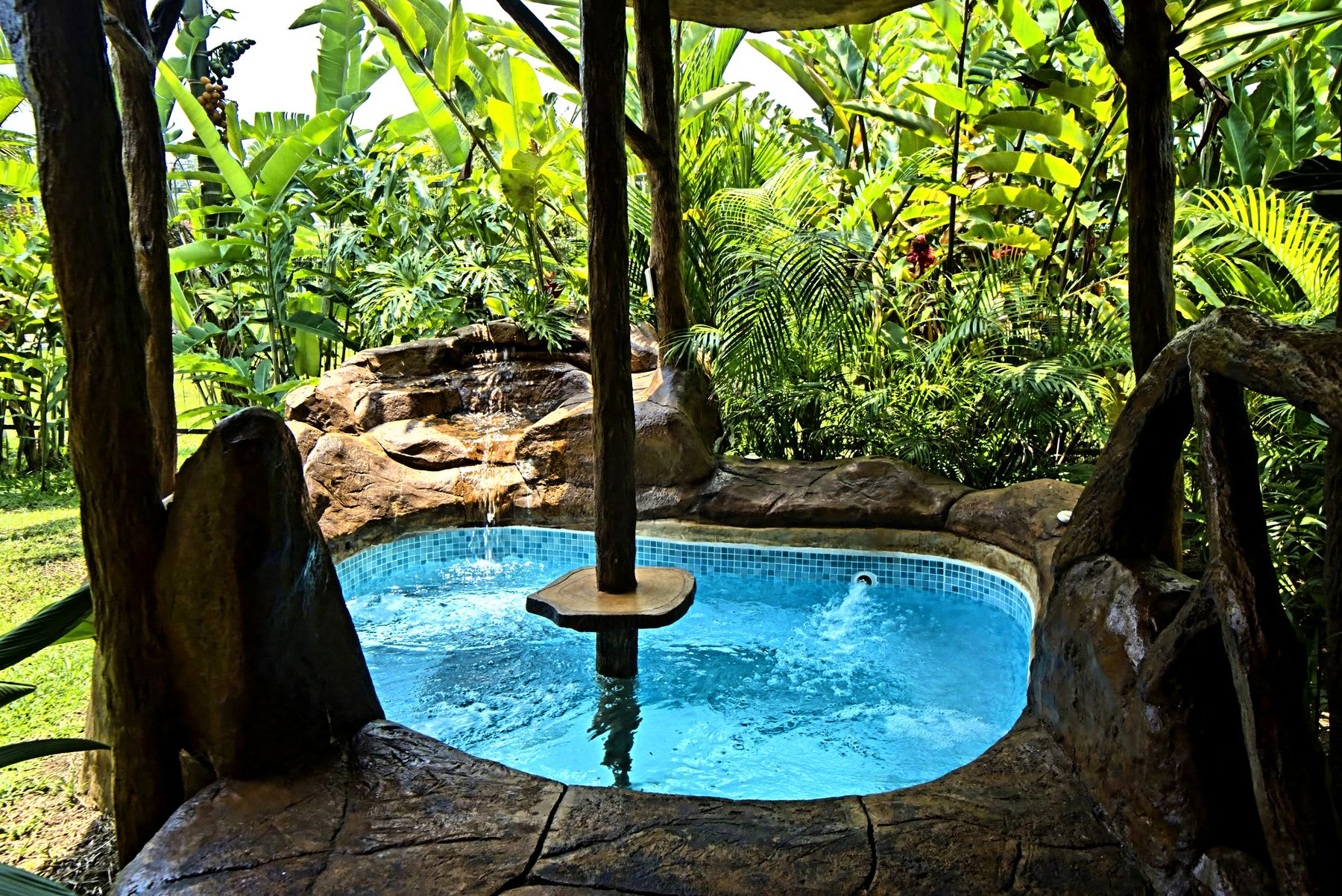 Private jacuzzi at Arenal Rustic Villa, with a waterfall and tropical garden in La Fortuna.
