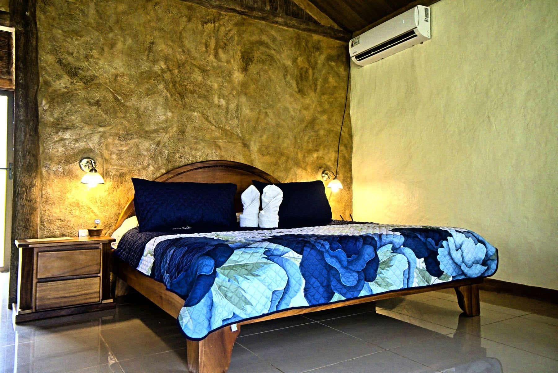 Bedroom with a king bed, air conditioning and a wood headboard.