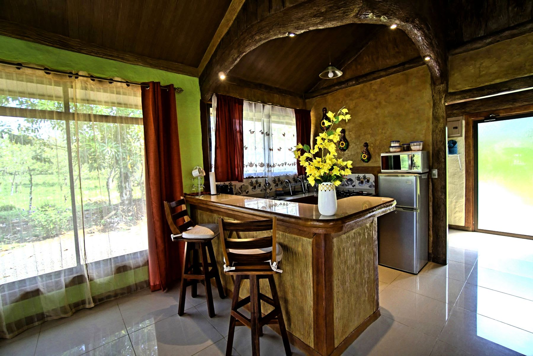 Kitchen with a breakfast bar, stools and a garden view.