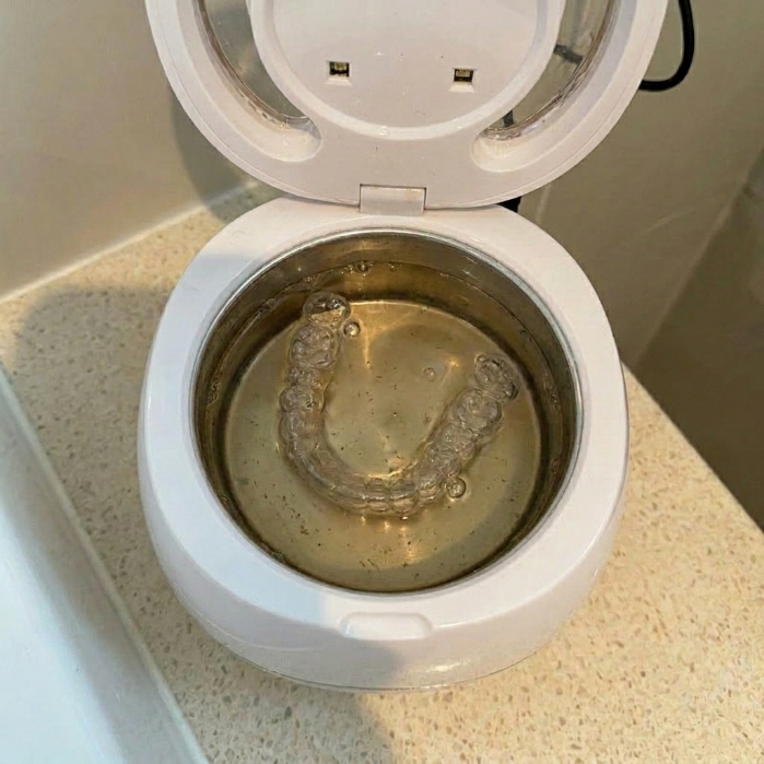 Ultrasonic cleaner showing brown water after cleaning cycle