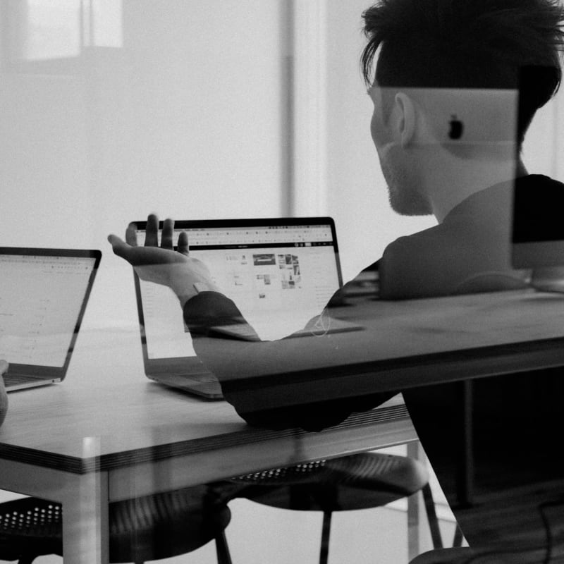 A person working on a laptop in black and white