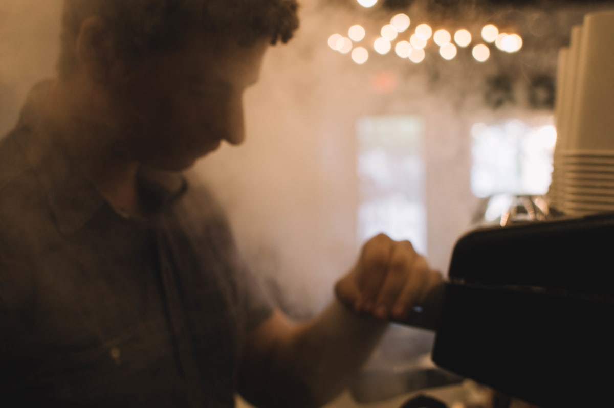 Barista working through espresso-machine steam