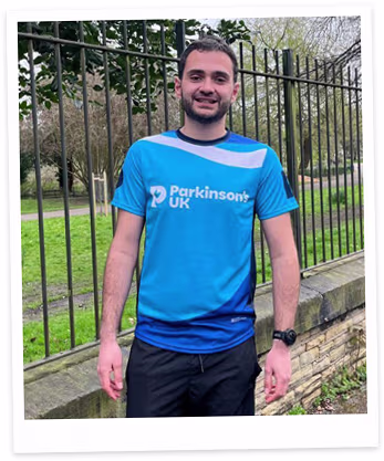 James standing outdoors in a 'Parkinson's UK' running shirt, ready for a charity marathon.