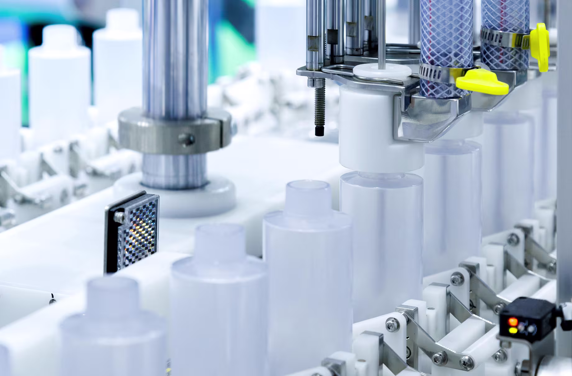 Laboratory or manufacturing equipment featuring white cylindrical tanks and mechanical components in a clean setting.