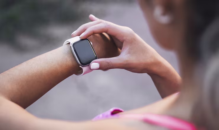 Person checking a smartwatch on their wrist outdoors.