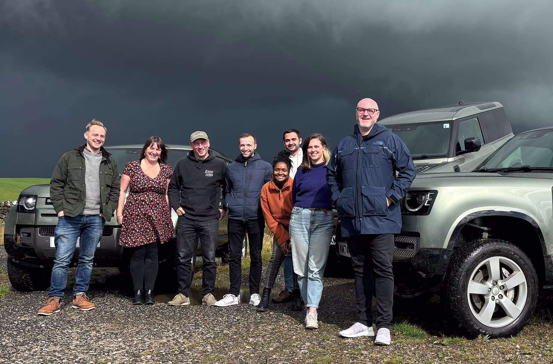 True9 team members standing in front of Land Rover vehicles during a team building event