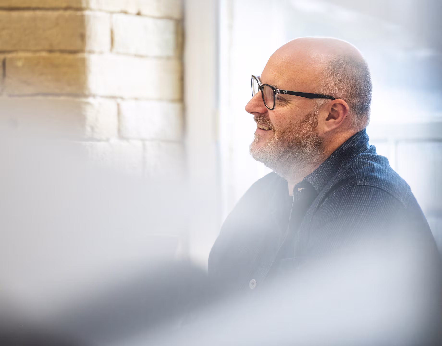 Close-up profile of a smiling male designer with glasses, representing a focus on user-centered design and empathy