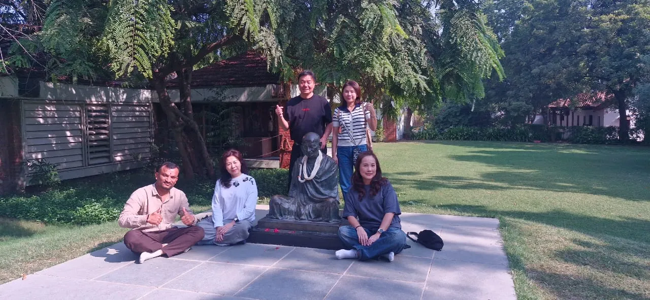 旅客们围坐在绿树成荫的花园雕像旁