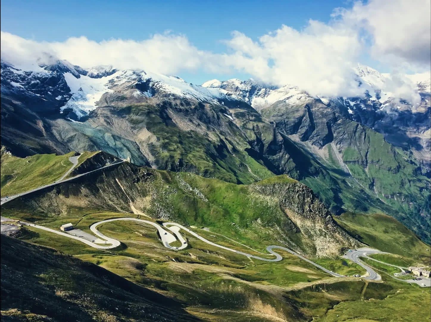 Winding path on a mountain with vegetation and snow on the summit, Grossglockner High Alpine Road