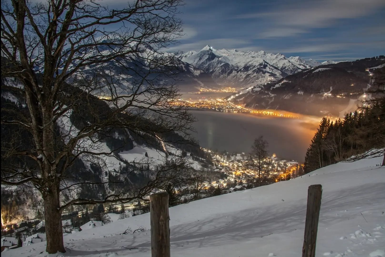 View from above of a village nestled between mountains at night, Zell am See