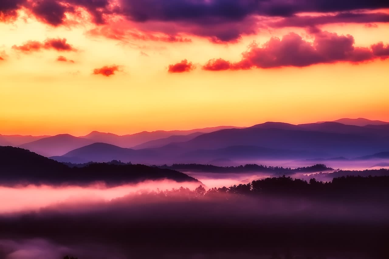 Sunset over the Great Smoky Mountains, casting a golden glow over the dense forests and misty ridges