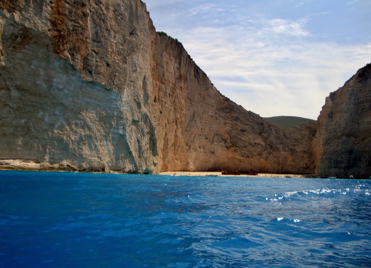 Aerial view of Navagio Shipwreck Beach enclosed by white limestone cliffs with turquoise Ionian water and rusting wreck Zakynthos Greece