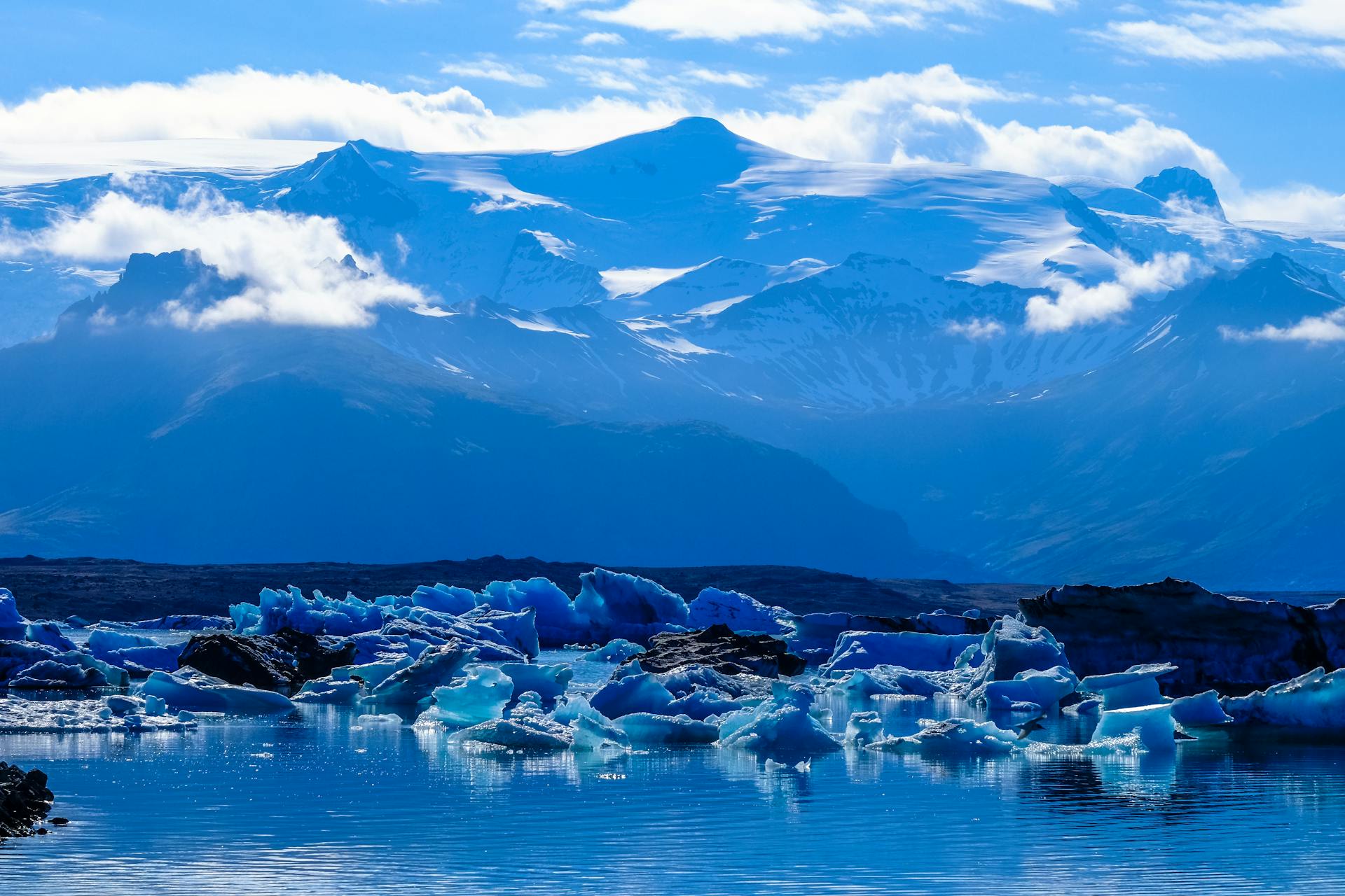 Northern lights reflected in the still water of Jökulsárlón surrounded by glowing icebergs
