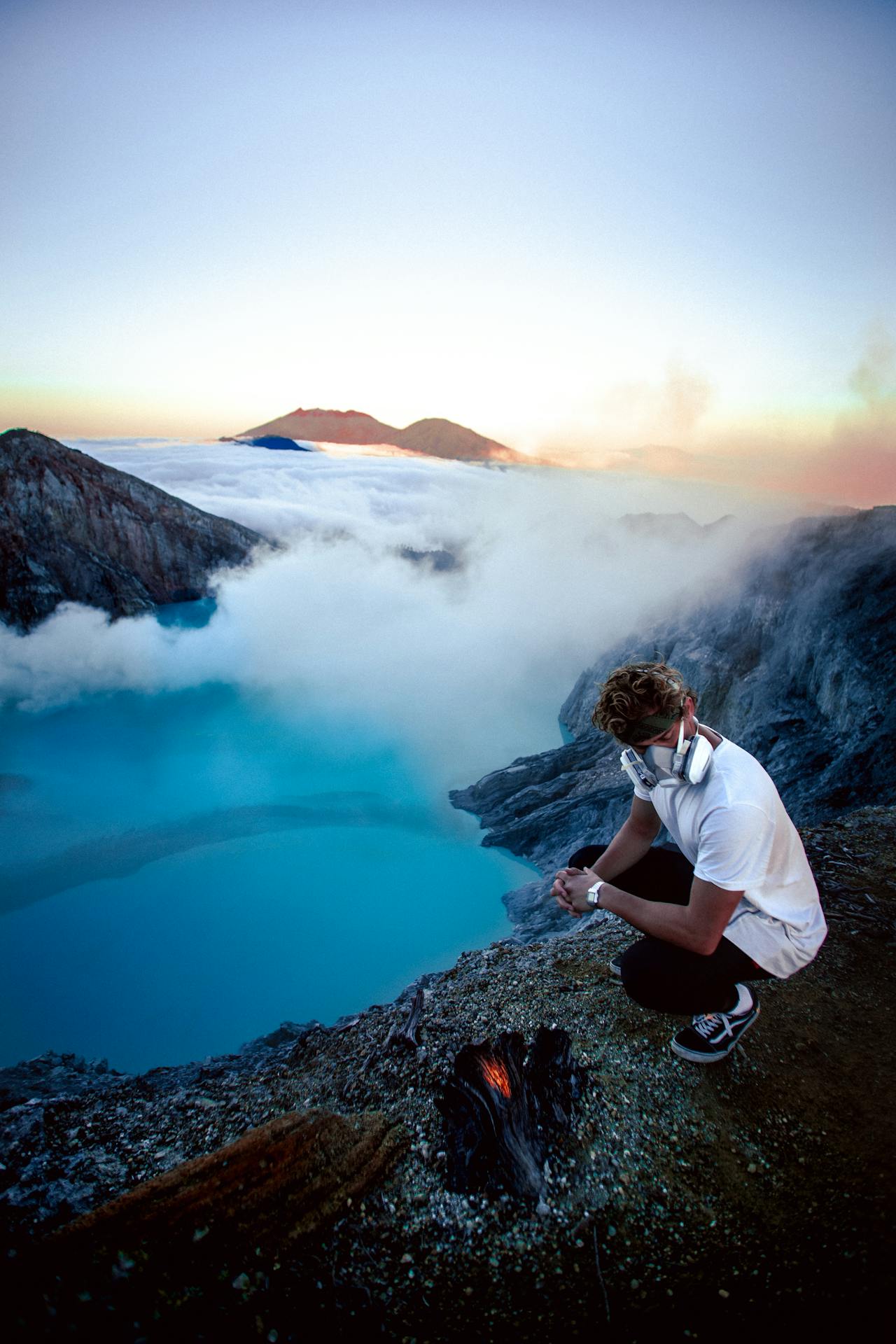 Dawn light over the Kawah Ijen crater rim with the turquoise lake below and volcanic landscape around