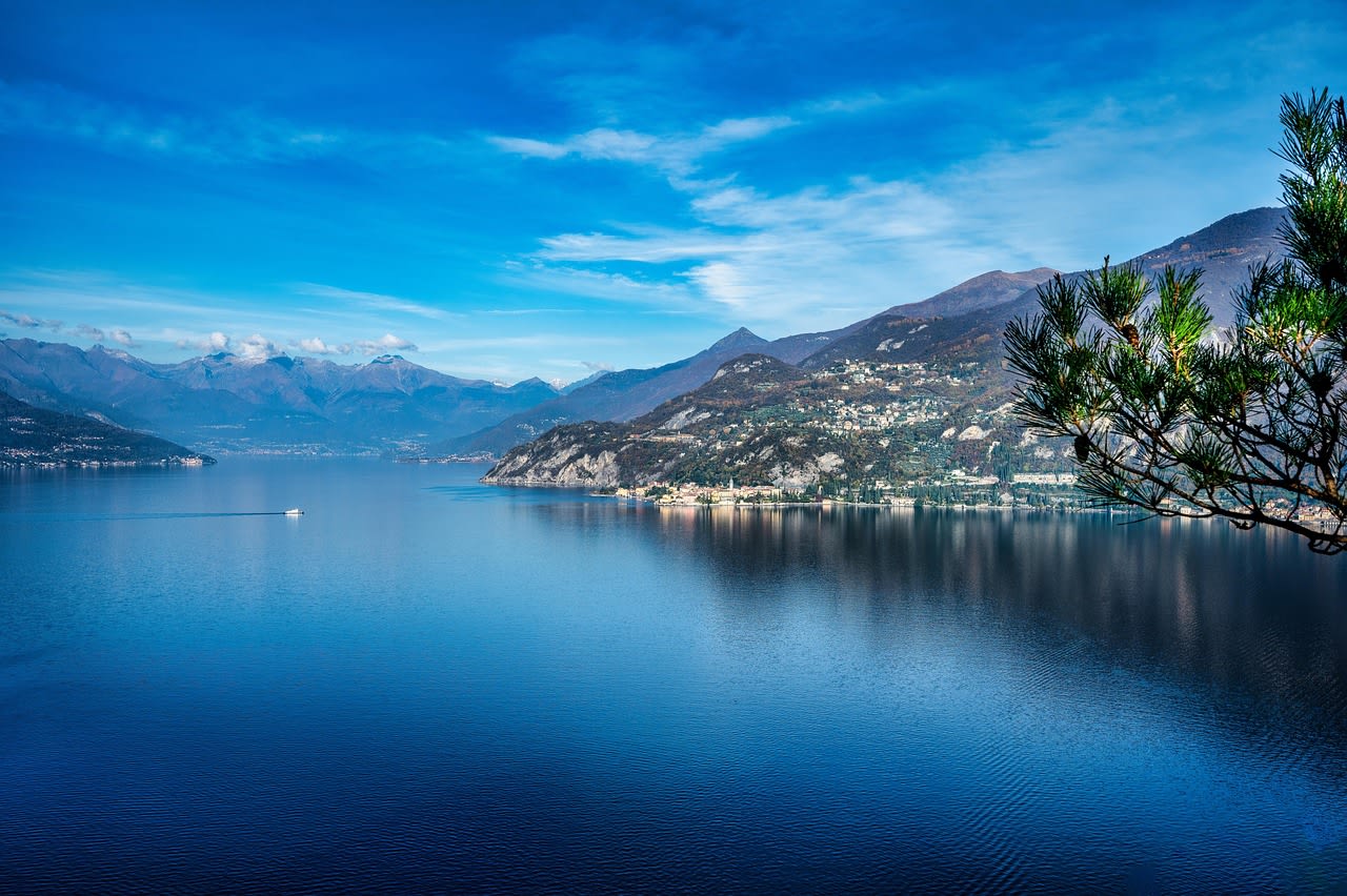 Bellagio village on the promontory between the two branches of Lake Como with lakeside gardens and Alps behind