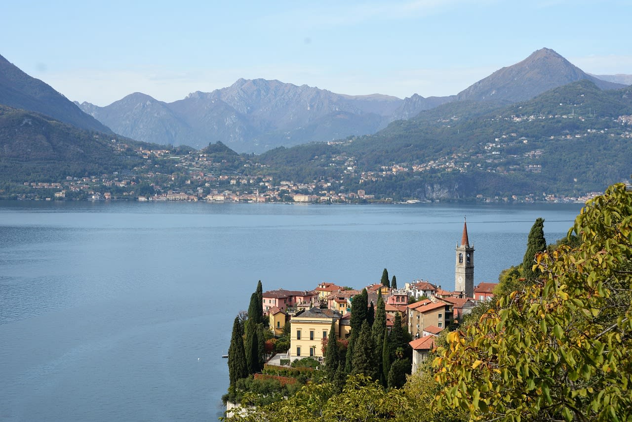 Traditional wooden Lario boat on Lake Como at dusk with mountain silhouettes and terracotta village rooftops