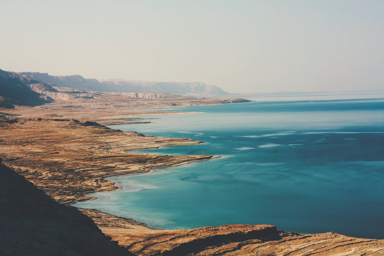 Bather floating in the Dead Sea with the Jordanian cliffs of the Jordan Rift Valley behind