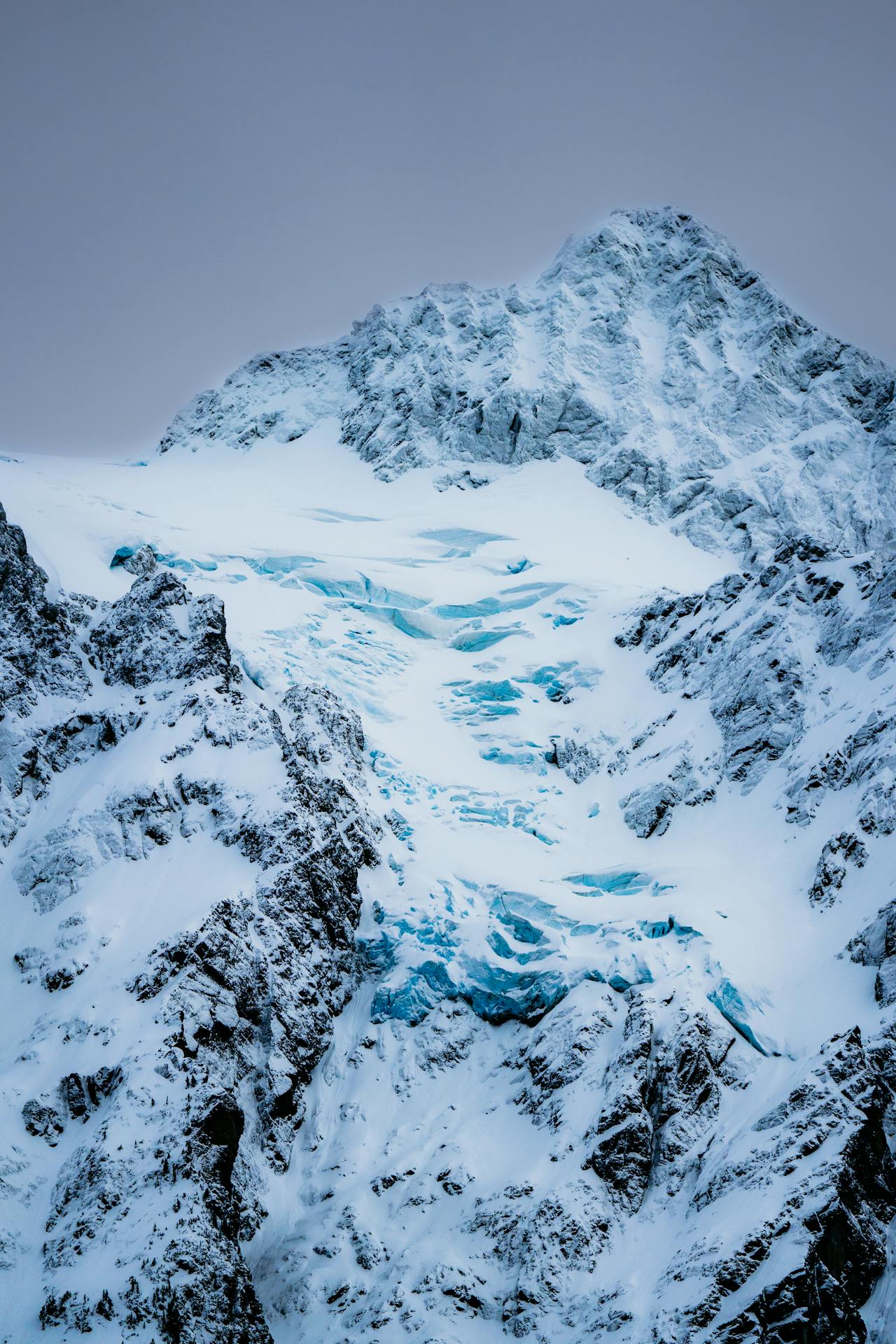 Aerial view of Fox Glacier curving through the Southern Alps in a valley of snow and rock
