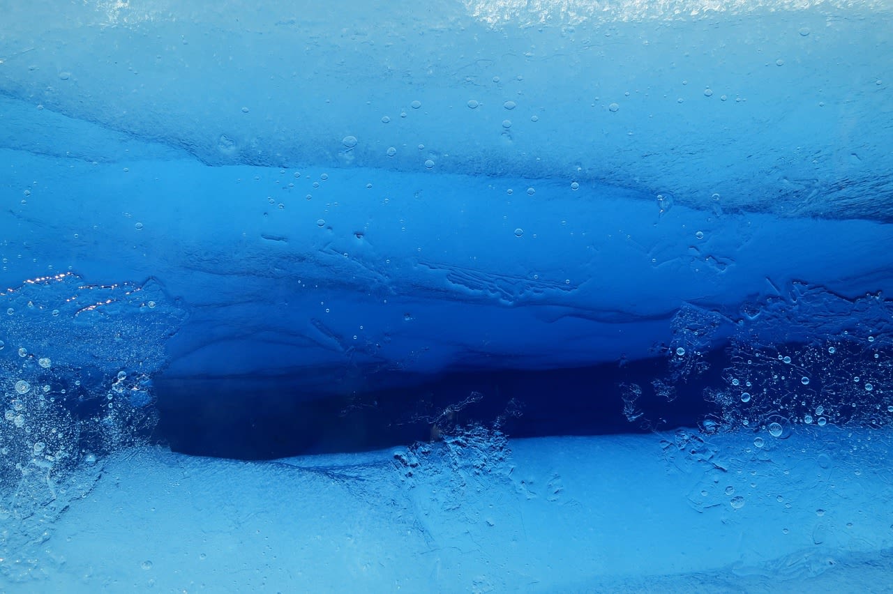 Blue ice cave interior of Fox Glacier with crevasse walls glowing electric blue in New Zealand