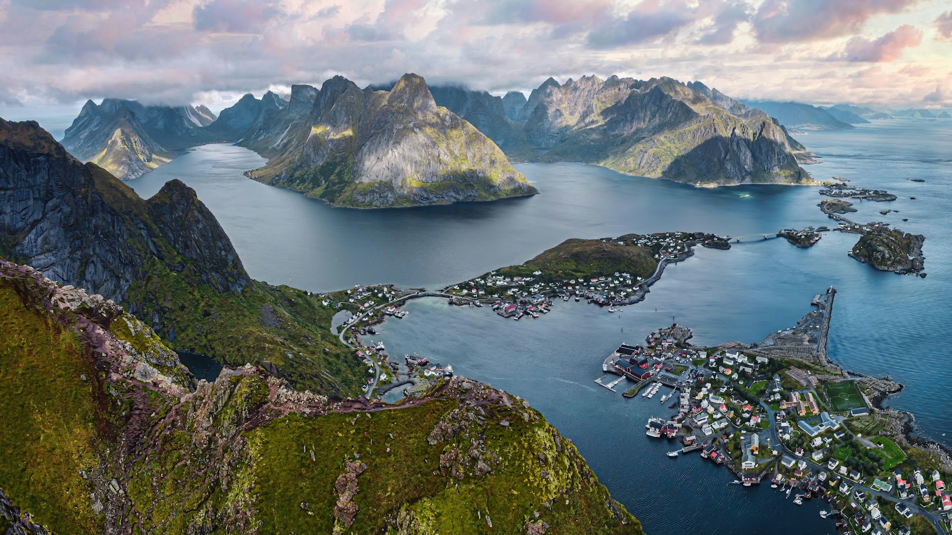 Lofoten Islands dramatic peaks and rorbu cabins reflected in fjord water, Arctic Norway