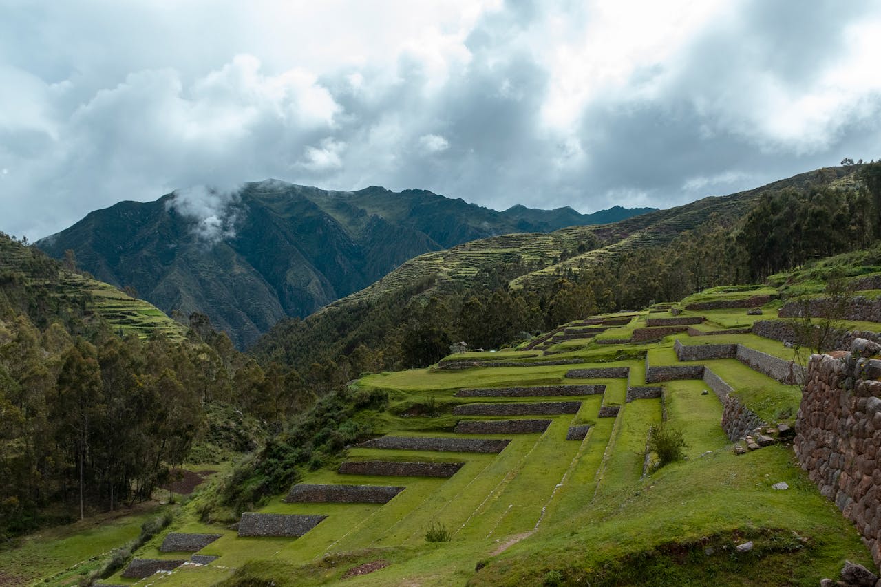 Inca agricultural terraces and hilltop ruins in the Sacred Valley with Andean peaks behind Peru